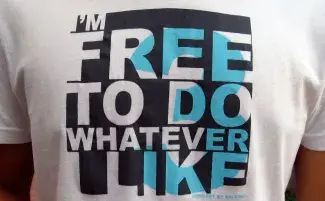 The chest of an unidentifiable wearer is puffed up to highlight their white t-shirt which reads I’M FREE TO DO WHATEVER I LIKE, written in white block letters against a black square with a sky blue number three peaking through the stencilled graphic text. 