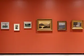 Six landscape paintings are hung against a vermillion wall. The frames are shifted up and down on the wall inorder to align the horizon lines of each different forest setting. 