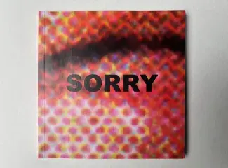 A pink and yellowy orange moire pattern coats the cover of a square book. SORRY is written in all capitals in bold black font across the centre, just under a shadowy curve in the pattern which looks like a pouting bottom lip.