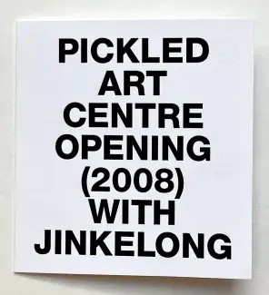  A white square of cardstock is filled with the words PICKED ART CENTRE OPENING (2008) WITH JINKELONG in bold black sans serif capitals. 